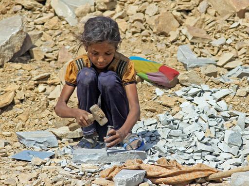Ein etwa 8-jähriges Mädchen sitzt am 16.05.2013 in Kota, in der indischen Provinz Rajasthan, in einem Steinbruch und arbeitet mit Hammer und Meißel.