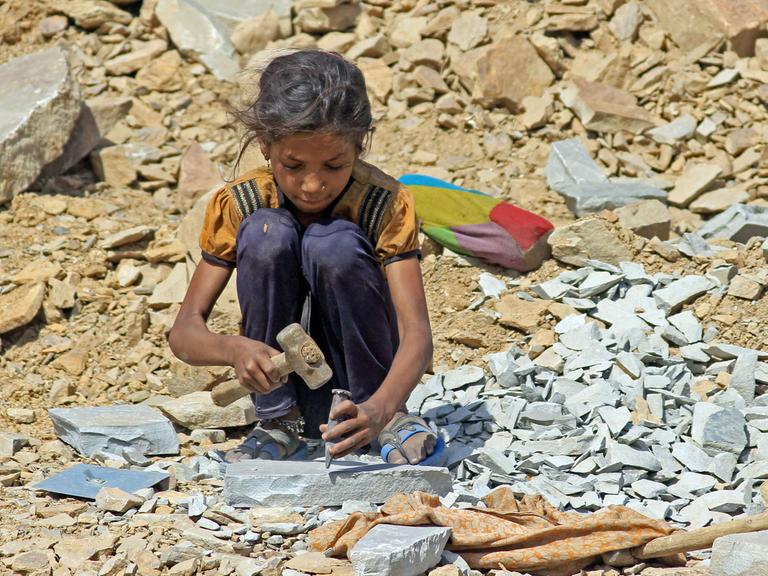 Ein etwa 8-jähriges Mädchen sitzt am 16.05.2013 in Kota, in der indischen Provinz Rajasthan, in einem Steinbruch und arbeitet mit Hammer und Meißel.