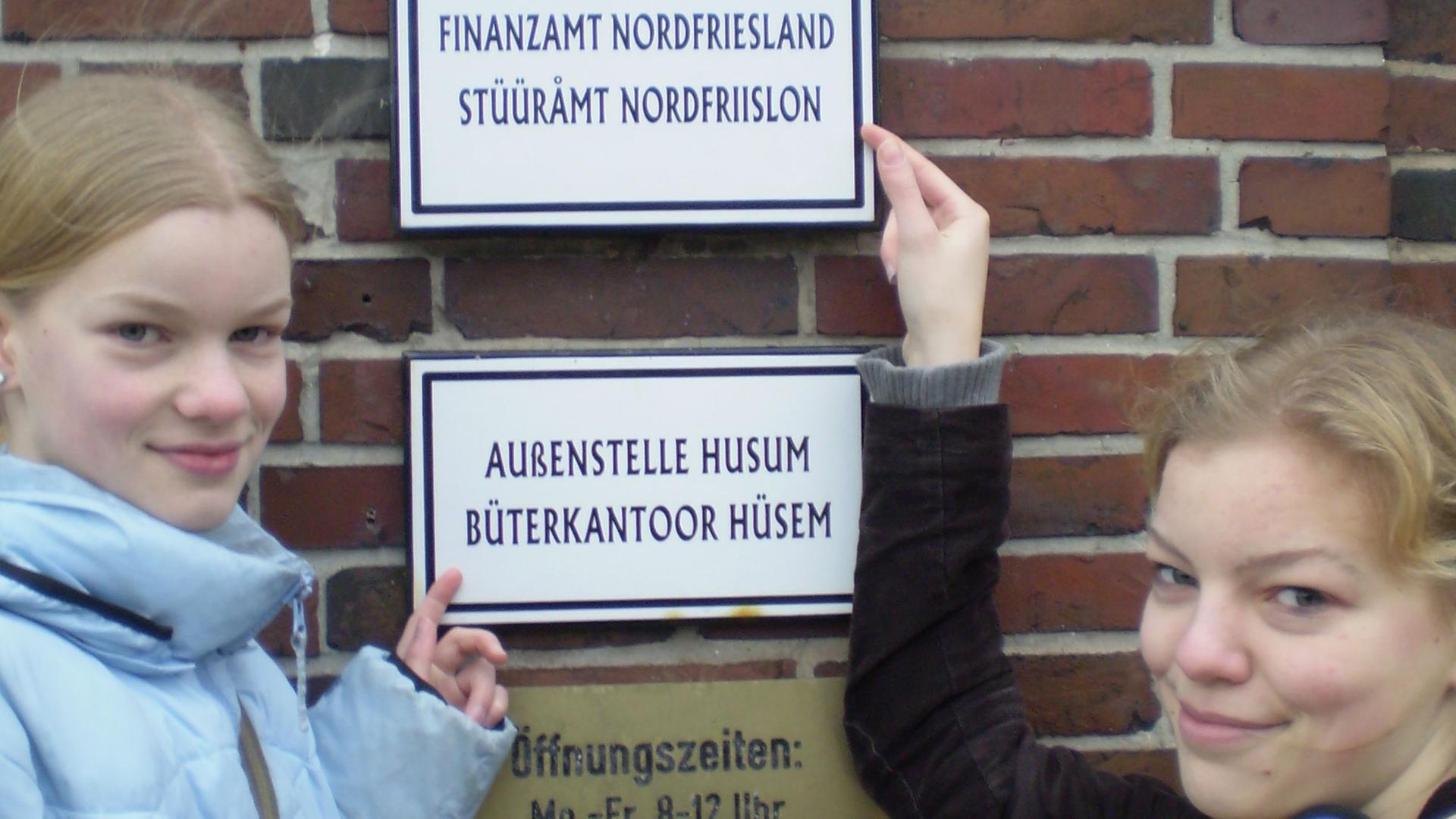 Zwei Friesinnen zeigen stolz das zweisprachige Schild am Finanzamt in Husum Zwei Friesinnen zeigen stolz das zweisprachige Schild am Finanzamt in Husum