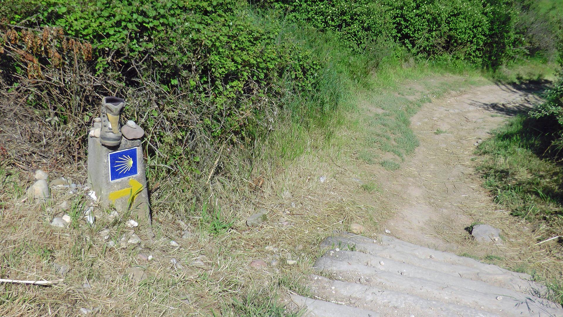 Verlaufen ist fast nicht möglich, so gut ist der Jakobsweg, der Camino, gekennzeichnet: Hier ein Wegstein mit Wanderschuh, Stein und Muschelsymbol in der Nähe des spanischen Ortes Maneru. Verlaufen ist fast nicht möglich, so gut ist der Jakobsweg, der Camino, gekennzeichnet: Hier ein Wegstein mit Wanderschuh, Stein und Muschelsymbol in der Nähe des spanischen Ortes Maneru.