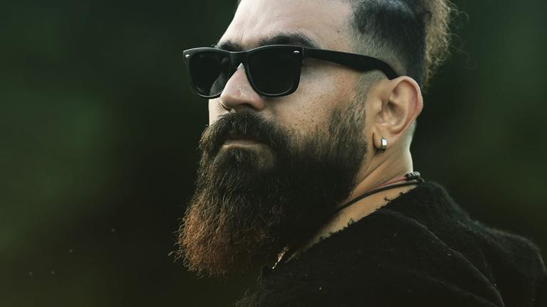 Shekib Mosadeq trägt auf dem Foto eine Sonnenbrille. Er hat einen Rauschebart und dunkle Haare. Shekib Mosadeq trägt auf dem Foto eine Sonnenbrille. Er hat einen Rauschebart und dunkle Haare.