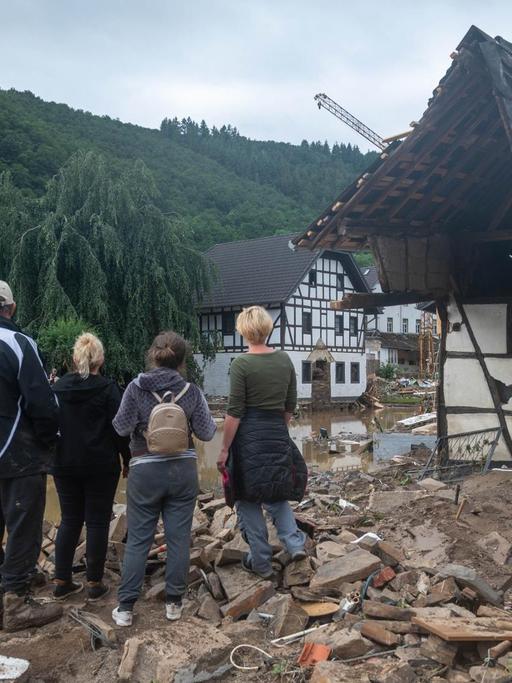 Eine Gruppe von Menschen schaut in dem Ort im Kreis Ahrweiler nach dem Unwetter auf die Zerstörungen.