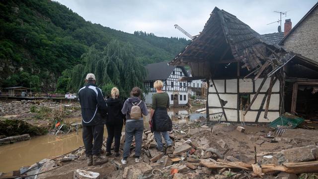 Eine Gruppe von Menschen schaut in dem Ort im Kreis Ahrweiler nach dem Unwetter auf die Zerstörungen.