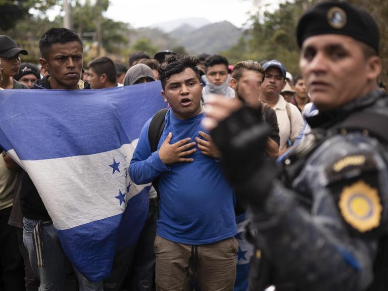 Flüchtlinge aus Honduras werden an der Grenze zu Guatemala vom Grenzschutz aufgehalten. Einer von ihnen schwenkt die honduranische Flagge.