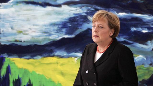 Angela Merkel vor einem gelb, grünen, schwarzen Bild im Bundeskanzleramt