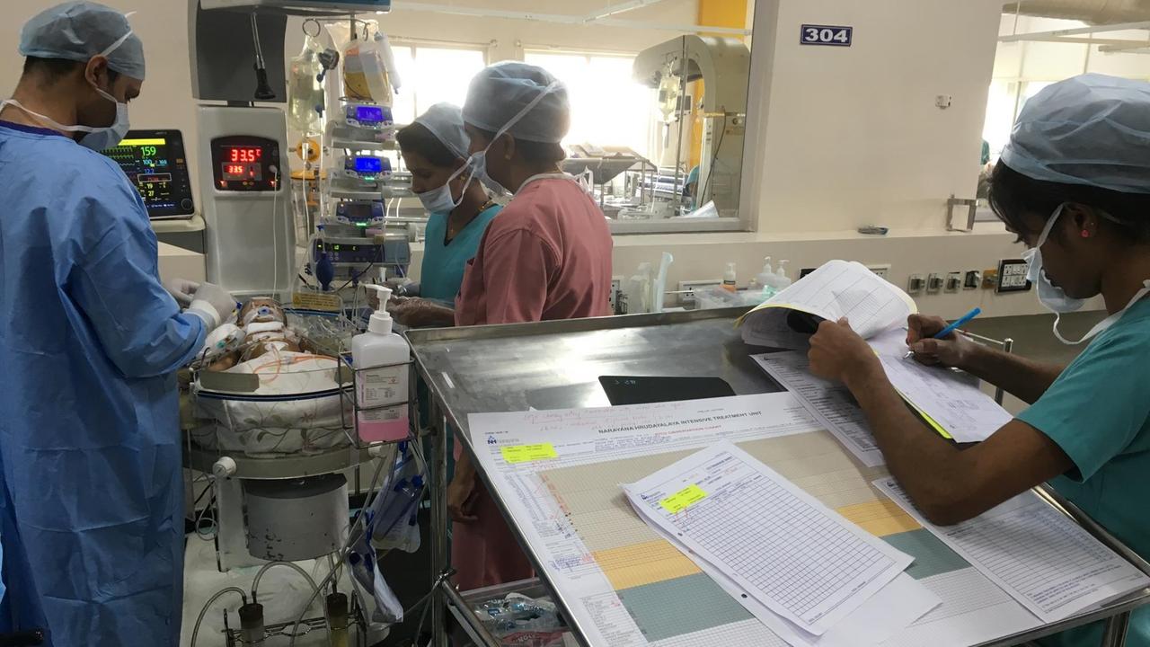 Ärzte stehen um das Bett eines operierten Säuglings