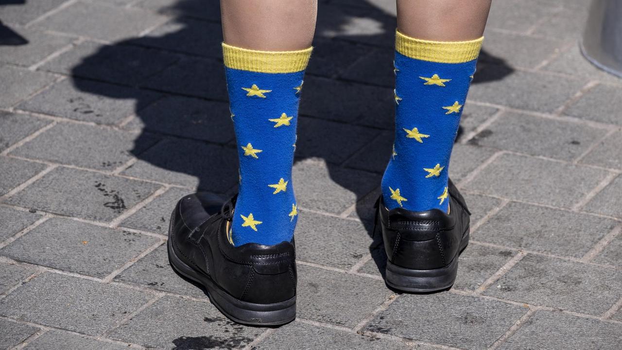Eine Person trägt hochgezogene Socken im Design der europäischen Flagge.