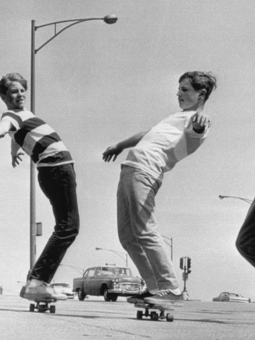 Eine s/w Aufnahme vom Mai 1965 zeigt vier Jungen aus Chicago, die auf ihren Skateboards über den Bürgersteig balancieren.