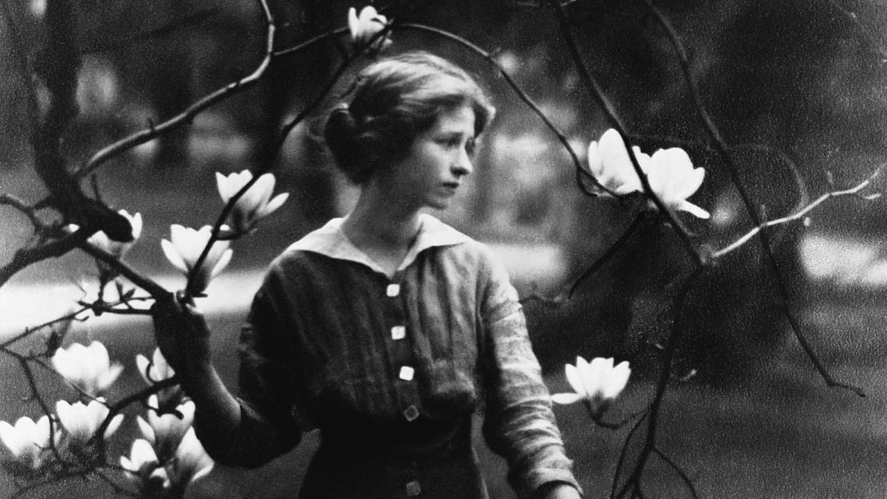 Historische Fotografie von Edna St. Vincent Millay hinter den Ästen eines blühenden Magnolienbaums, 1931