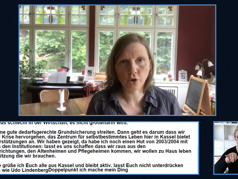 In einem Fenster des Livestreams spricht eine Frau, darunter sieht man eine Gebärdendolmetscherin und ein Fester mit Untertiteln.