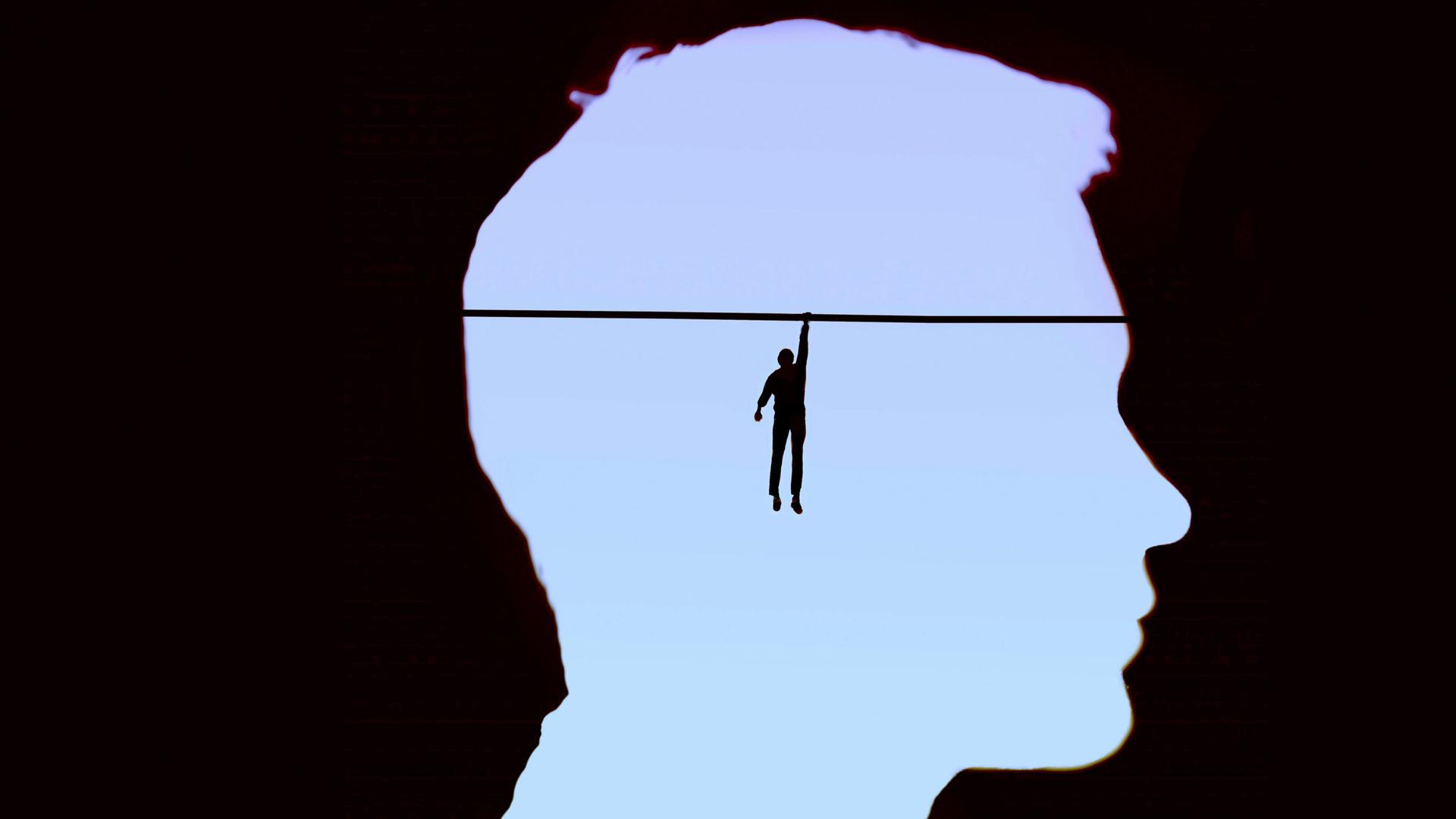 Eine Illustration zeigt im Kopf eines Mannes einen Mensch, der sich an ein Seil klammert. Eine Illustration zeigt im Kopf eines Mannes einen Mensch, der sich an ein Seil klammert.