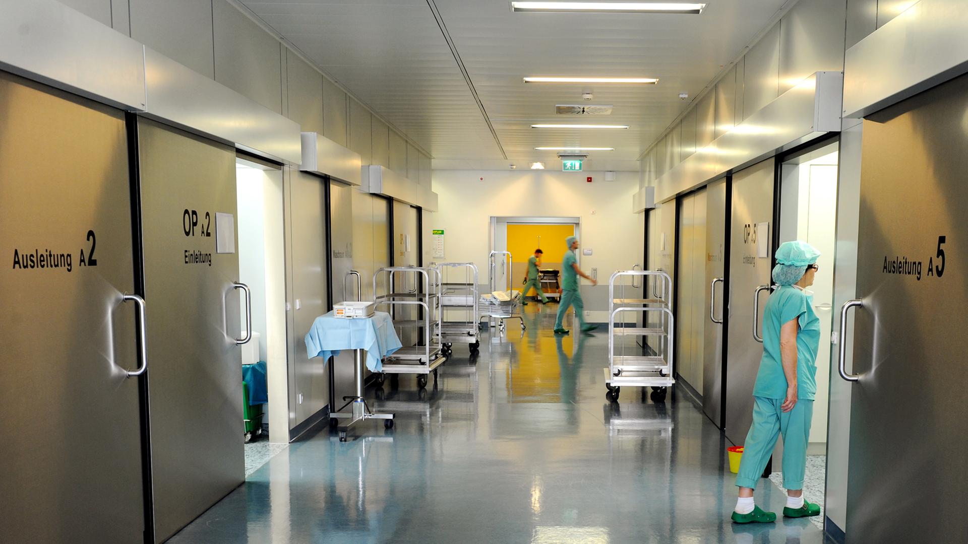 In einem Krankenhaus laufen Mitarbeiter über den Flur. In einem Krankenhaus laufen Mitarbeiter über den Flur.