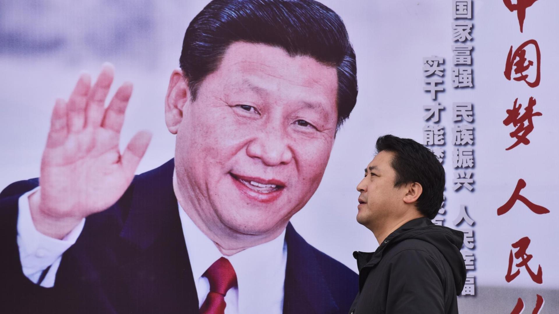 Ein Mann läuft in Peking an einem Poster mit Xi Jinping und der Aufschrift "Chinas Traum, des Volkes Traum" vorbei. Ein Mann läuft in Peking an einem Poster mit Xi Jinping und der Aufschrift "Chinas Traum, des Volkes Traum" vorbei.