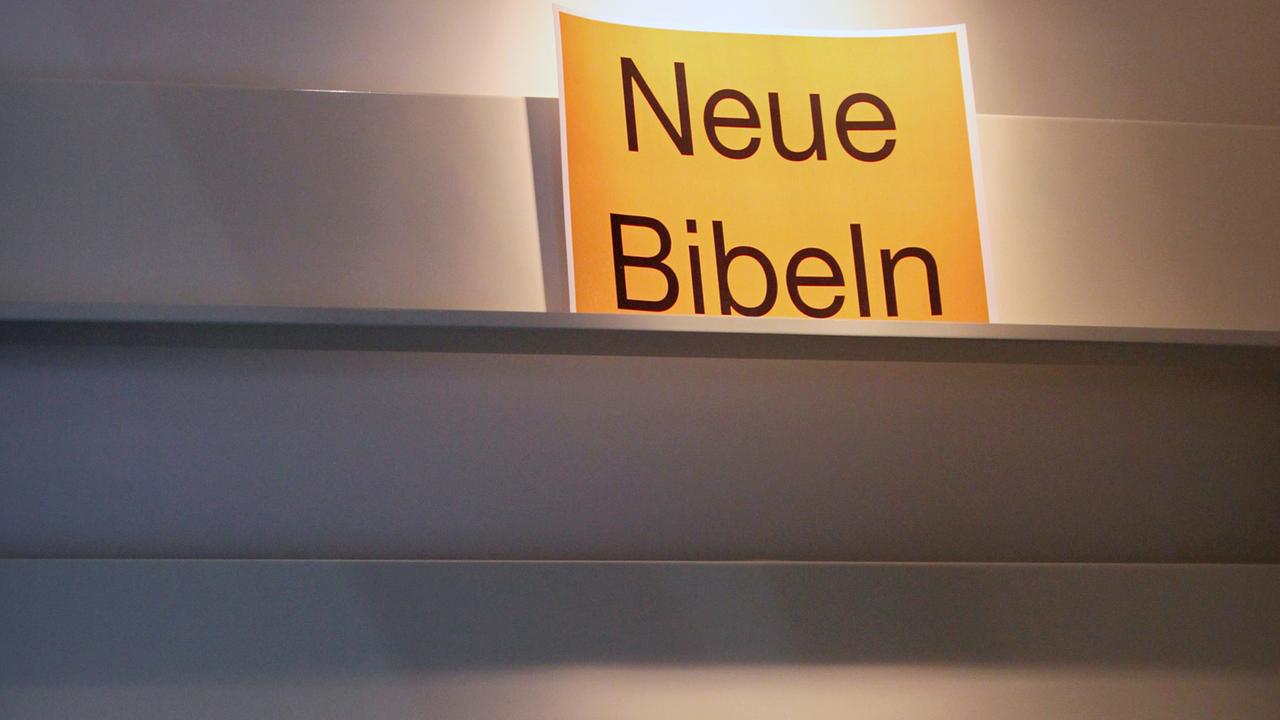 Ein Schild "Neue Bibeln" steht in einem leeren Bücherregal Ein Schild "Neue Bibeln" steht in einem leeren Bücherregal