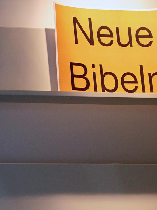 Ein Schild "Neue Bibeln" steht in einem leeren Bücherregal