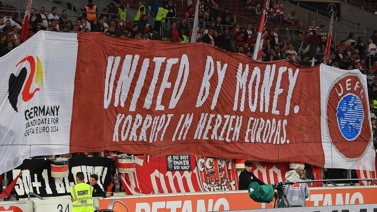 Plakat wird im Stadion hochgehalten: Korrupt im Herzen von Europa, United by Money Plakat wird im Stadion hochgehalten: Korrupt im Herzen von Europa, United by Money