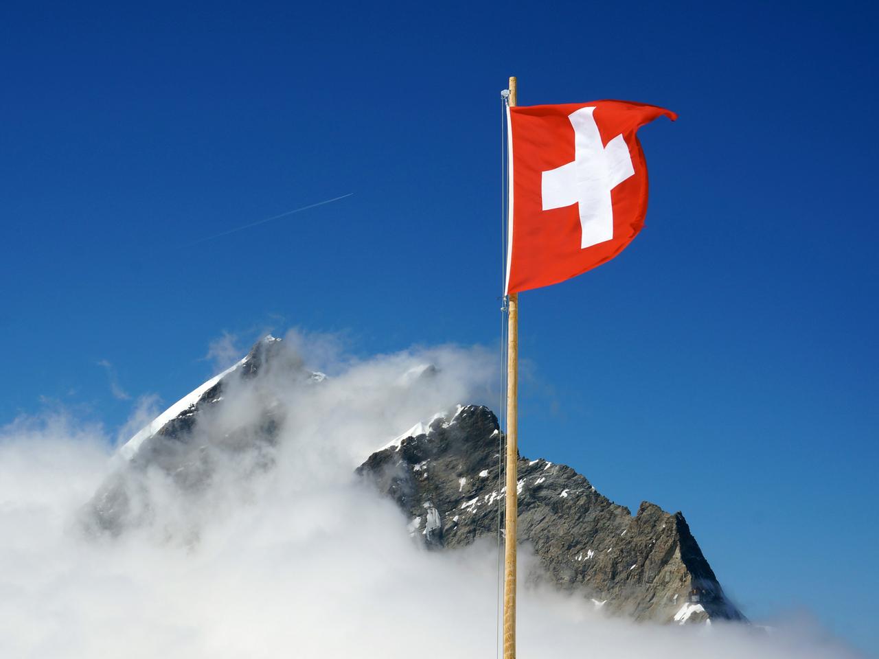 Die Schweizer Flagge weht nahe dem Jungfraujoch in den Berner Alpen in der Schweiz Die Schweizer Flagge weht nahe dem Jungfraujoch in den Berner Alpen in der Schweiz