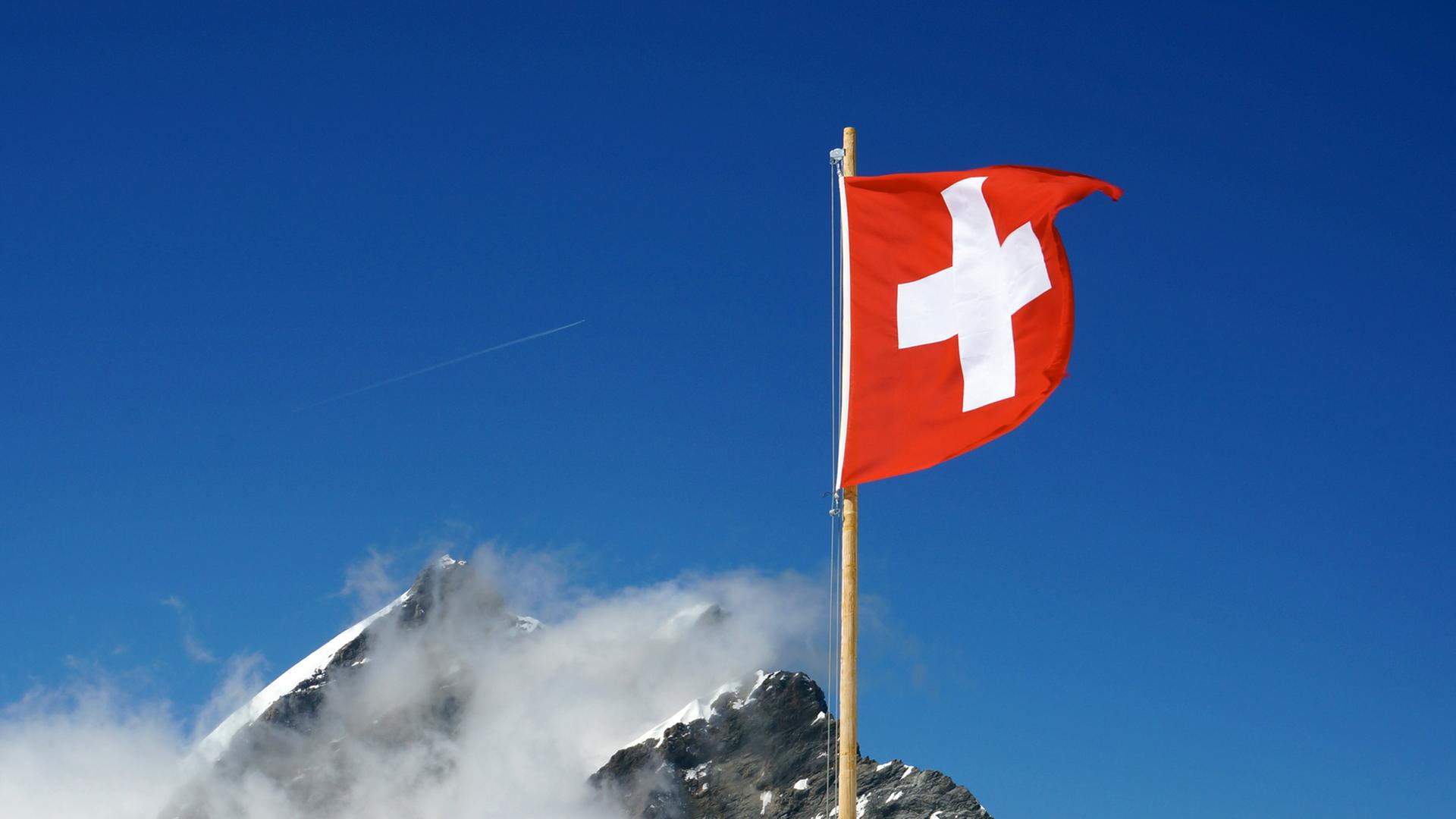 Die Schweizer Flagge weht vor klarem Himmel in den Berner Alpen.