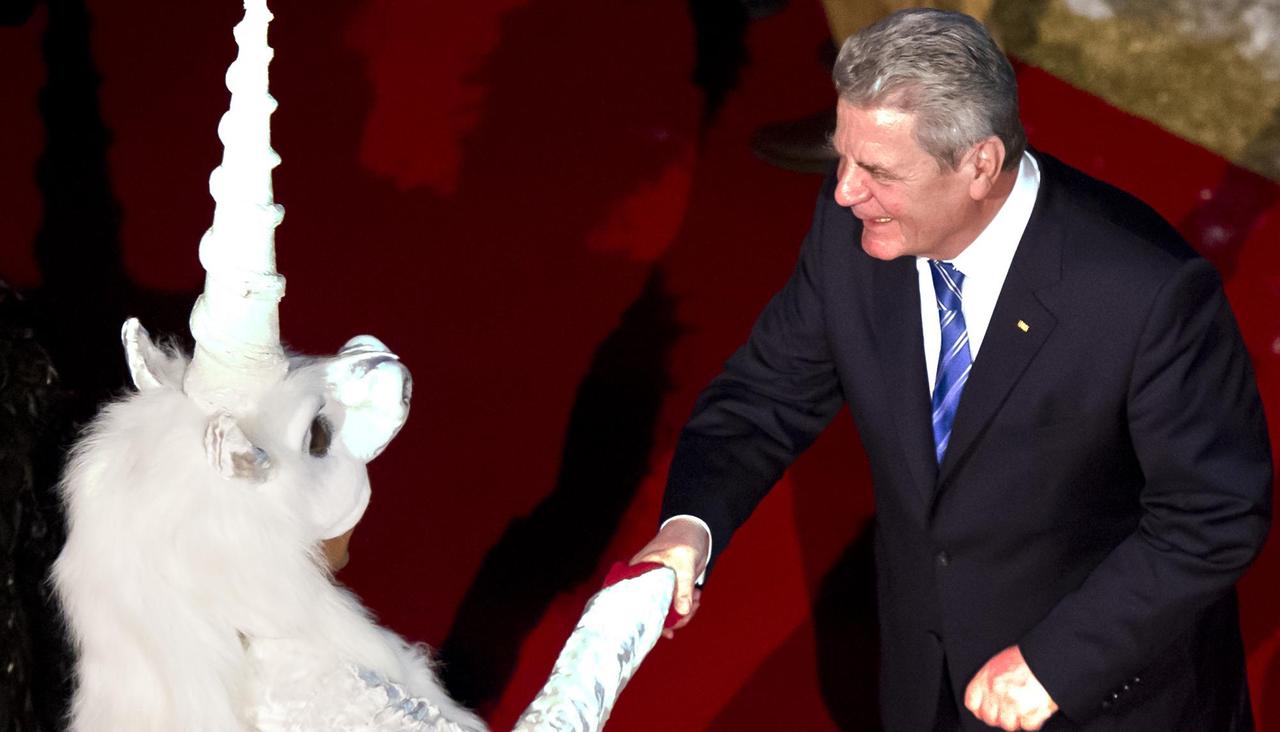 Bundespräsident Joachim Gauck bei einem Besuch in Hessen. Er wird von einer jungen Frau im Einhorn-Kostüm begrüßt. Bundespräsident Joachim Gauck bei einem Besuch in Hessen. Er wird von einer jungen Frau im Einhorn-Kostüm begrüßt.