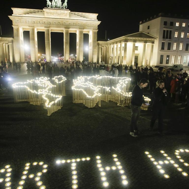 Das Brandenburger Tor ohne Beleuchtung. Auf dem Boden leuchtende Buchstaben, die den Begriff "Earth Hour" bilden.
