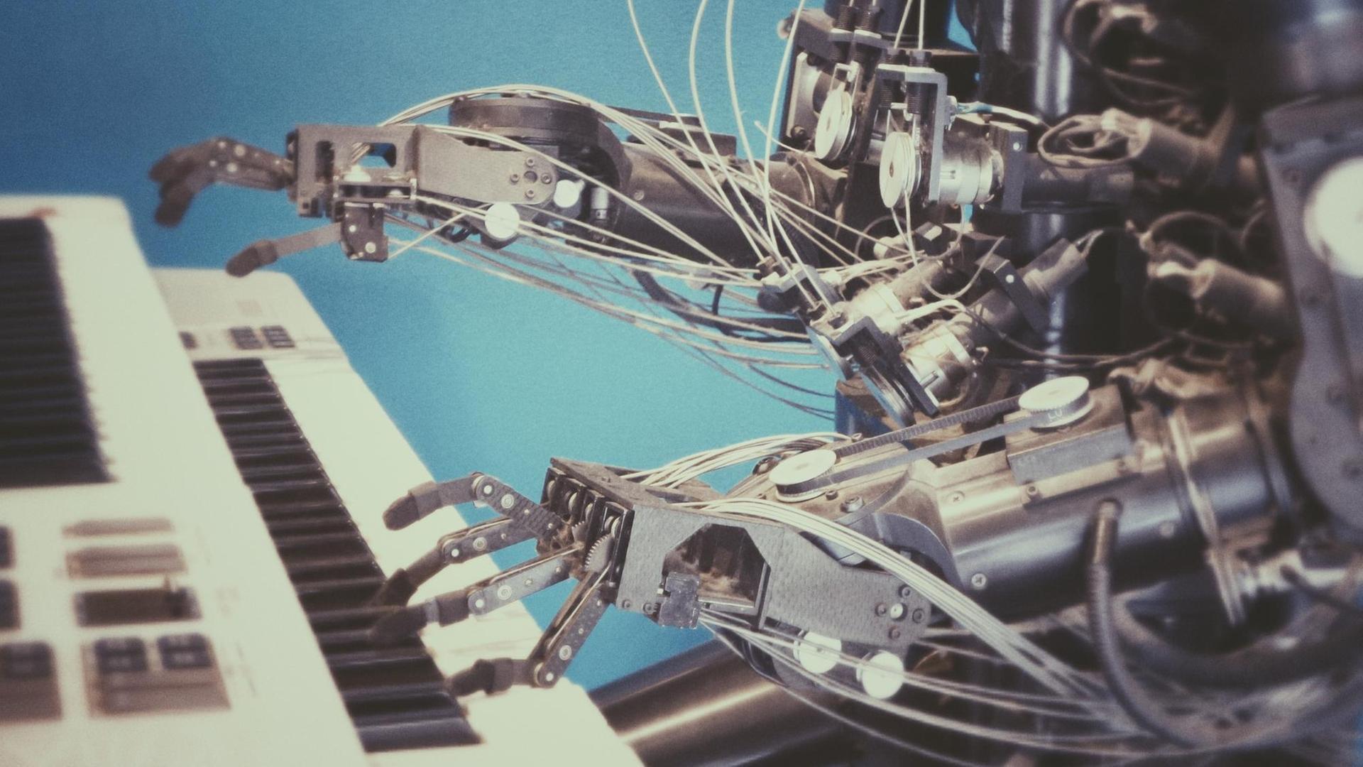 Metallene Robotter-Arme spielen auf einem weißen Piano. Metallene Robotter-Arme spielen auf einem weißen Piano.