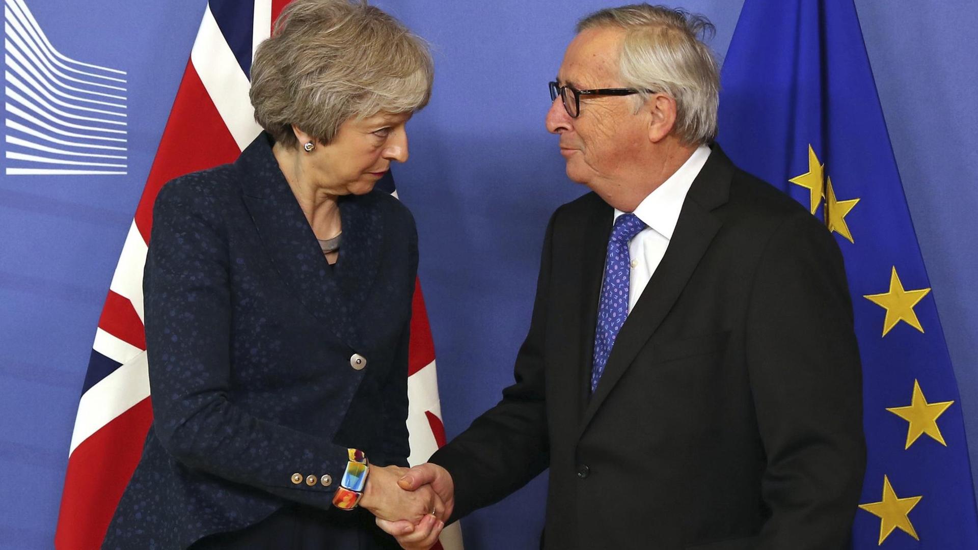 Die britische Premierministerin May schüttelt dem EU-Kommissionspräsidenten Juncker die Hand. Die britische Premierministerin May schüttelt dem EU-Kommissionspräsidenten Juncker die Hand.