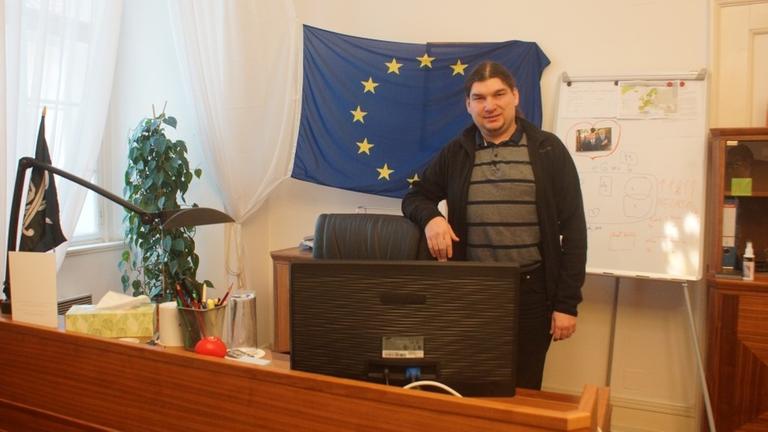 Pirat Ondrej Profant war bei der Gründung der Partei vor zehn Jahren dabei und ist heute Abgeordneter im tschechischen Parlament. Hier steht er in seinem Büro. An der Wand eine EU-Flagge.