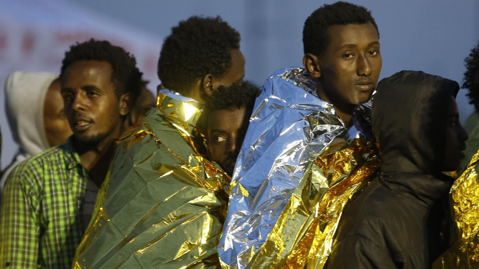 Afrikanische Flüchtlinge auf Sizilien sind in Wärmedecken eingehüllt. Afrikanische Flüchtlinge auf Sizilien sind in Wärmedecken eingehüllt.