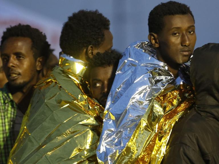 Afrikanische Flüchtlinge auf Sizilien sind in Wärmedecken eingehüllt.