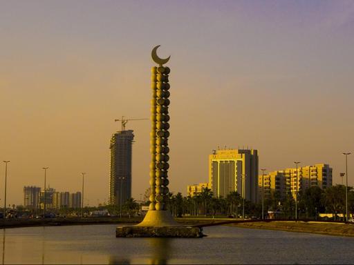 Eine Ansicht auf die saudi-arabische Hafenstadt Dschidda. Im Vordergrund ein Monument mit einem Halbmond, im Hintergrund Hochhäuser.