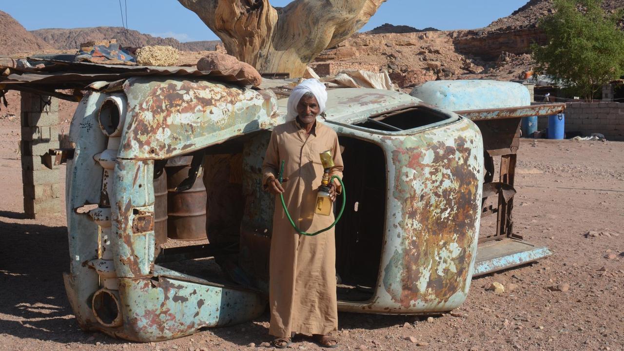 Ibrahim ist der Mann von Umm Yasser und unterstützt sie bei ihrer Arbeit als erste Wanderführerin der Beduinen-Gesellschaft auf dem Sinai. Er steht vor einem umgekippten Schrott-Auto in seinem Dorf. Ibrahim ist der Mann von Umm Yasser und unterstützt sie bei ihrer Arbeit als erste Wanderführerin der Beduinen-Gesellschaft auf dem Sinai. Er steht vor einem umgekippten Schrott-Auto in seinem Dorf.
