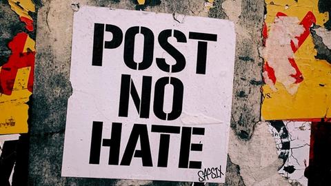 Ein Plakat auf einer Wand mit der Aufschrift "Post no hate"