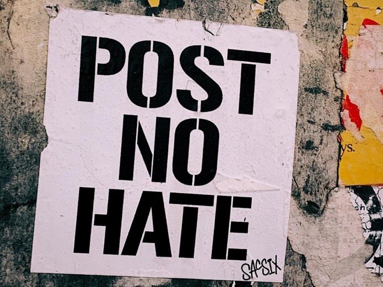 Ein Plakat auf einer Wand mit der Aufschrift "Post no hate"