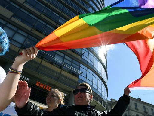 Russische Homosexuelle demonstrieren in Moskau für ihre Rechte. Sie halten bunte Fahnen.