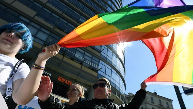 Russische Homosexuelle demonstrieren in Moskau für ihre Rechte. Sie halten bunte Fahnen.