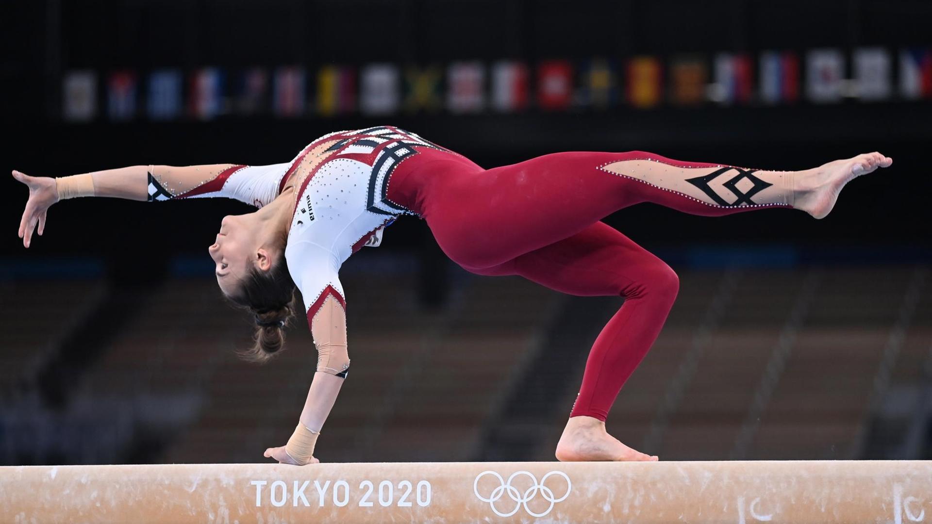 Eine Frau turnt bei den Olympischen Spielen auf einem Schwebebalken, Frauen, sie trägt einen bordeauxrot-weißen Ganzkörperanzug. Es handelt sich um die deutsche Turnerin Pauline Schäfer. Eine Frau turnt bei den Olympischen Spielen auf einem Schwebebalken, Frauen, sie trägt einen bordeauxrot-weißen Ganzkörperanzug. Es handelt sich um die deutsche Turnerin Pauline Schäfer.