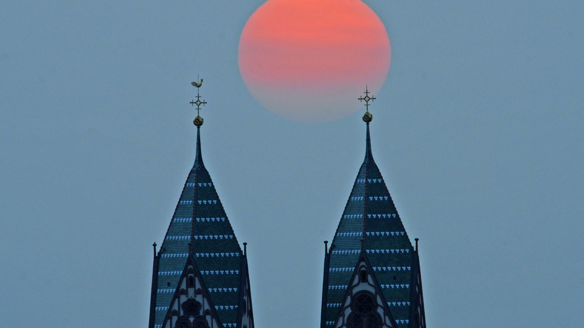 Die Sonne geht hinter den Türmen der Herz-Jesu-Kirche in Freiburg unter. Die Sonne geht hinter den Türmen der Herz-Jesu-Kirche in Freiburg unter.