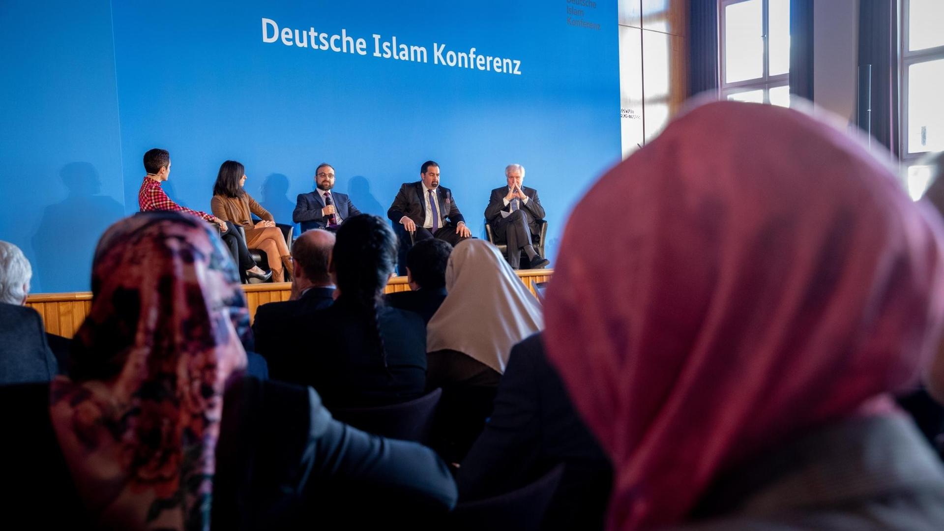 28.11.2018, Berlin: Serap Güler (l-r, CDU), Staatssekretärin für Integration im Ministerium für Kinder, Familie, Flüchtlinge und Integration, Bülent Ucar, deutsch-türkischer Islamwissenschaftler und Religionspädagoge, Aiman Mazyek, Vorsitzender des Zentralrats der Muslime in Deutschland, und Horst Seehofer (CSU), Bundesminister des Innern, für Bau und Heimat, nehmen an der Podiumsdiskussion der Auftaktveranstaltung zur 4. Deutschen Islam-Konferenz des Bundesinnenministeriums teil.