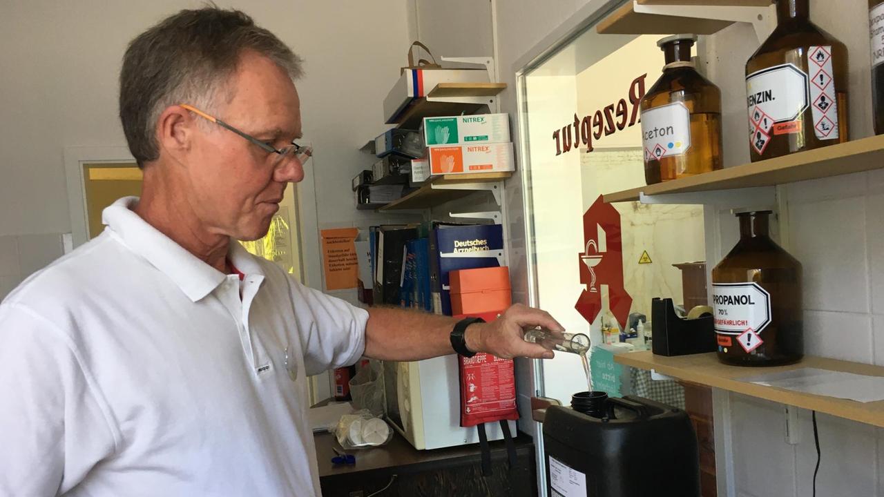 Der Apotheker Hans-Georg Hannappel füllt eine Flüssigkeit in einen Container um