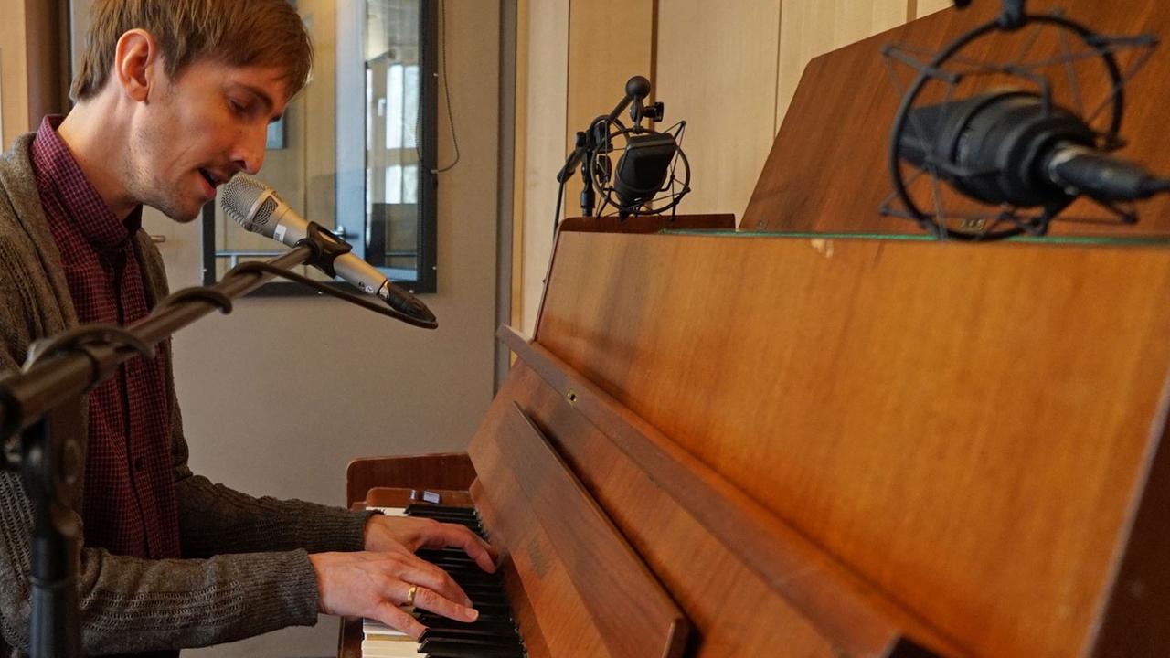 Helgi Jonsson am Klavier sich selbst begleitdent im Studio von Deutschlandfunk Kultur.