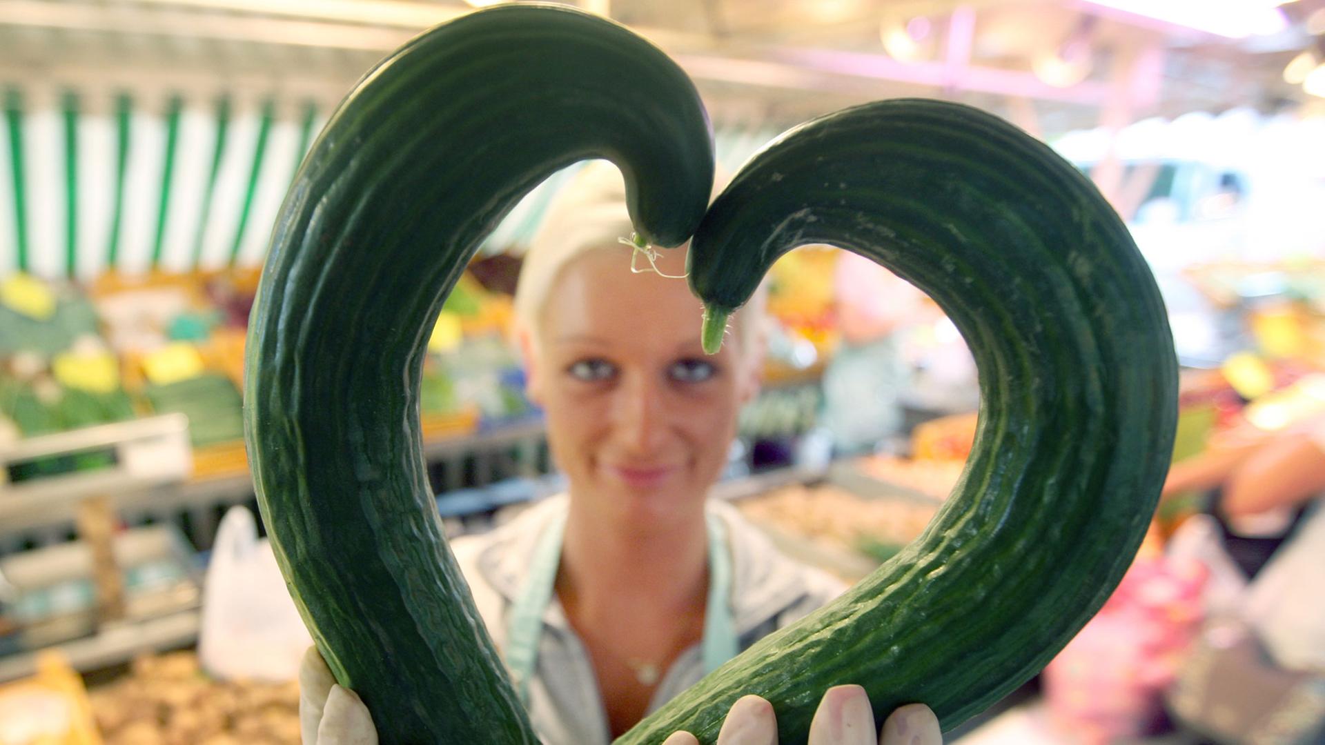 Eine Gemüsehändlerin zeigt am 30.06.2009 auf dem Isemarkt in Hamburg zwei krumme Gurken in Herzform. Eine Gemüsehändlerin zeigt am 30.06.2009 auf dem Isemarkt in Hamburg zwei krumme Gurken in Herzform.