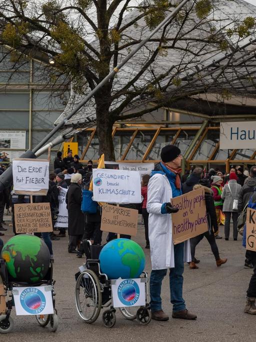 Klimaaktivisten demonstrieren mit Plakaten am Haupteingang zu Beginn der Siemens-Hauptversammlung vor der Olympiahalle in München.
