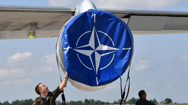 Mechaniker hanitieren auf der Internationalen Luft- und Raumfahrtmesse ILA an einer Schutzhülle mit dem Logo der Nato an einem AWACS Aufklärungsflugzeug.