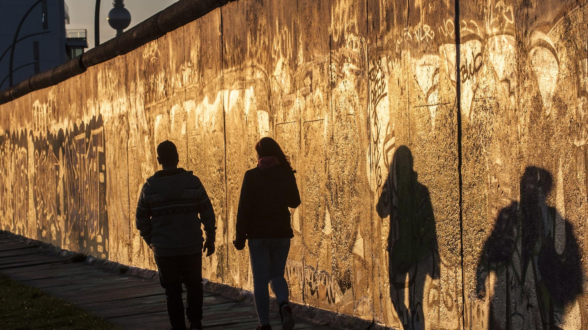 Eine Frau und ein Mann gehen am 18.04.2015 in Berlin im Licht der untergehenden Sonne an der East Side Gallery spazieren. Eine Frau und ein Mann gehen am 18.04.2015 in Berlin im Licht der untergehenden Sonne an der East Side Gallery spazieren.
