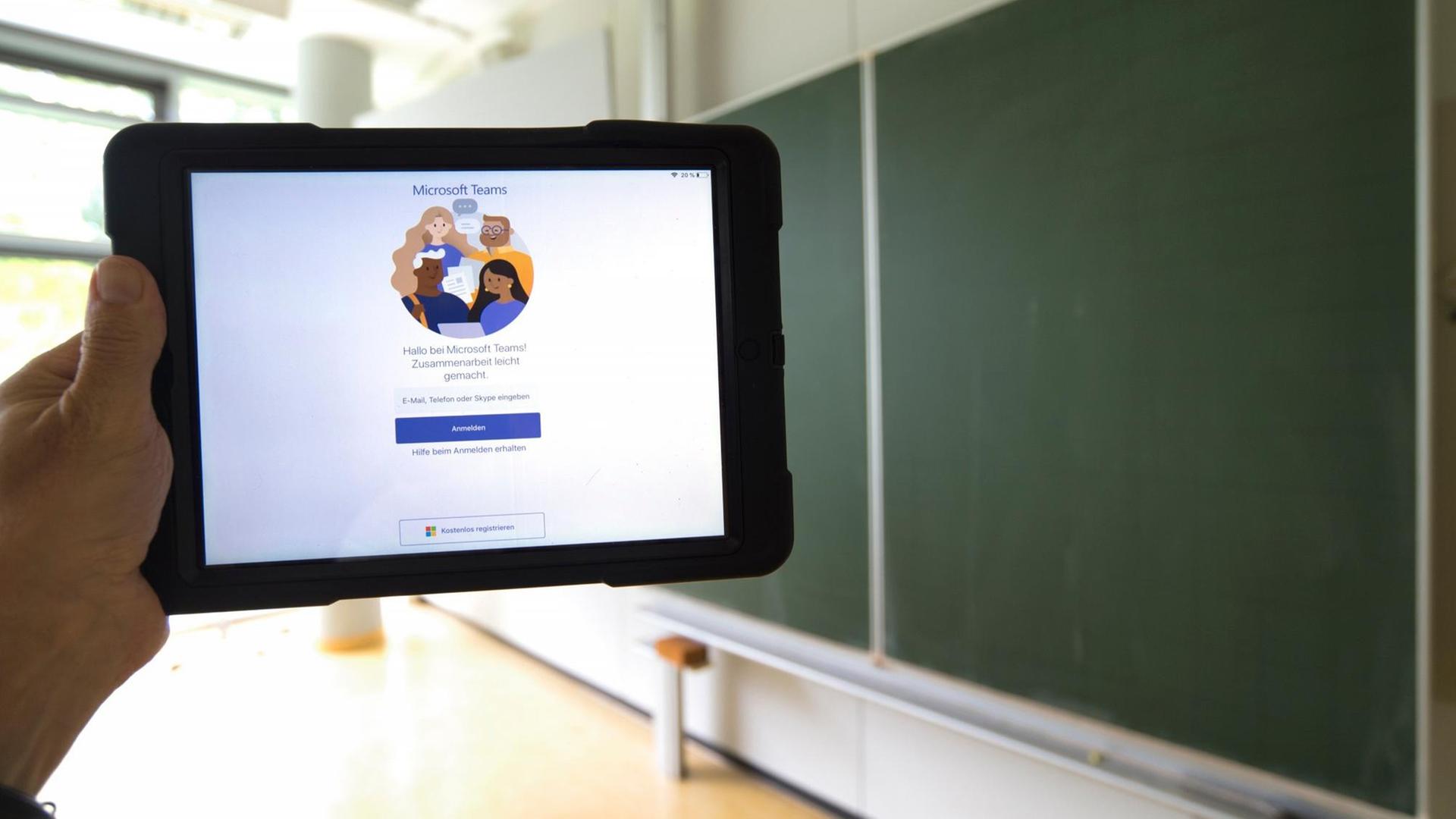 Ein Tablet mit Microsoft Teams vor einer Tafel in einem leeren Klassenzimmer Ein Tablet mit Microsoft Teams vor einer Tafel in einem leeren Klassenzimmer