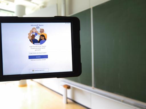 Ein Tablet mit Microsoft Teams vor einer Tafel in einem leeren Klassenzimmer 