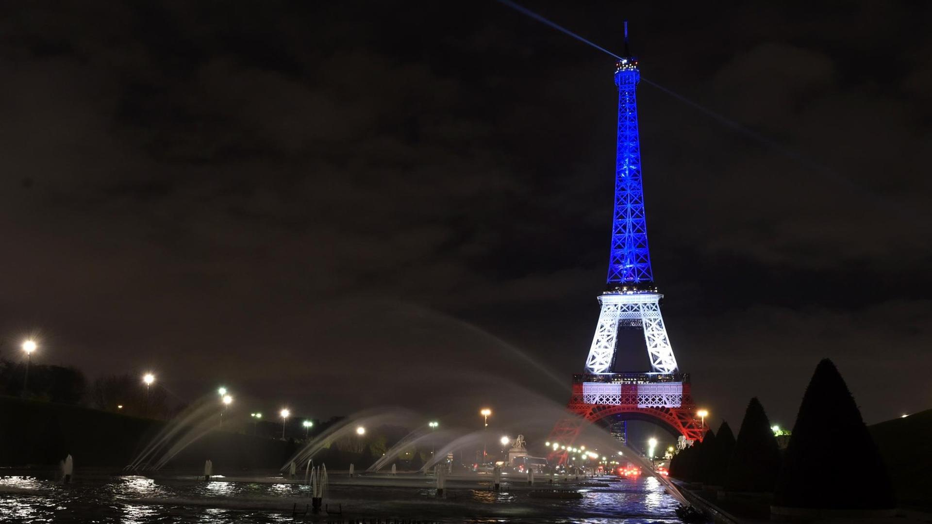 Nächtlicher Blick über die Seine auf den Eiffelturm, dessen oberer Teil blau, der mittlere Teil weiß und der untere Teil rot angestrahlt wird. Nächtlicher Blick über die Seine auf den Eiffelturm, dessen oberer Teil blau, der mittlere Teil weiß und der untere Teil rot angestrahlt wird.