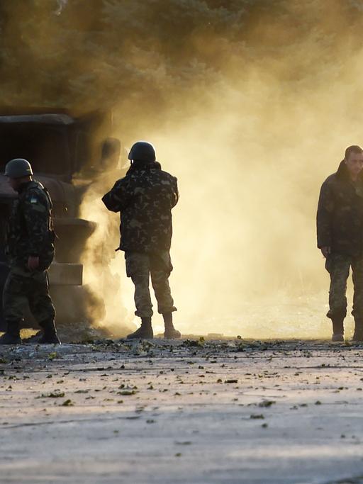 Ukrainische Soldaten stehen neben einem zerstörten Militärfahrzeug in der ostukrainischen Hafenstadt Mariupol.
