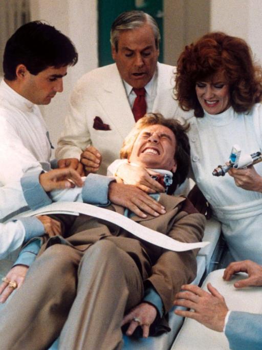 Martin Short liegt in der Filmszene festgezurrt auf einer Bare, umringt von 5 Ärzten mit einer riesigen Spritze.