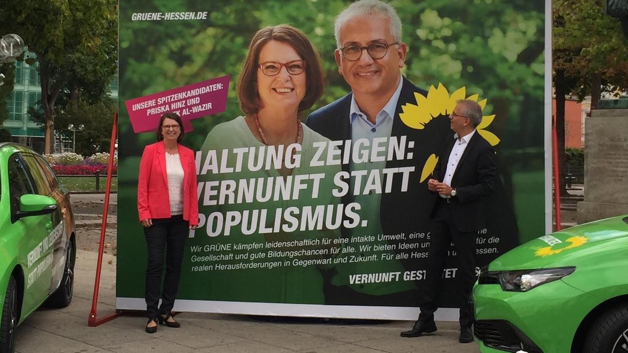 Die Spitzenkandidaten der Grünen für die Landtagswahl in Hessen, Priska Hinz und Tarek Al-Wazir, vor einem Wahlkampfplakat, das die beiden zeigt und mit dem Slogan "Haltung zeigen: Vernunft statt Populismus" versehen ist